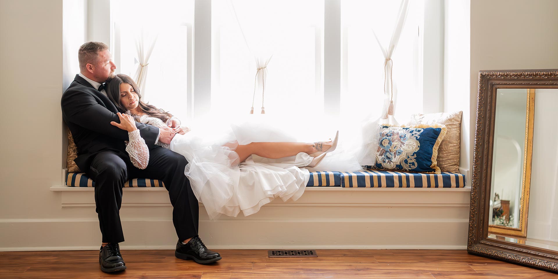 Groom and bride on bench with bride laying against groom
